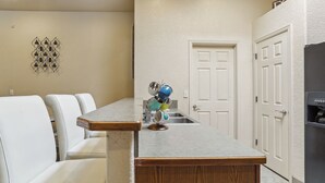 A kitchen with white cabinets, a wooden countertop, and a sink. There is a door and a refrigerator in the background. - Las Cruces Vacation Rental Near Trails & Golf! (Las Cruces)