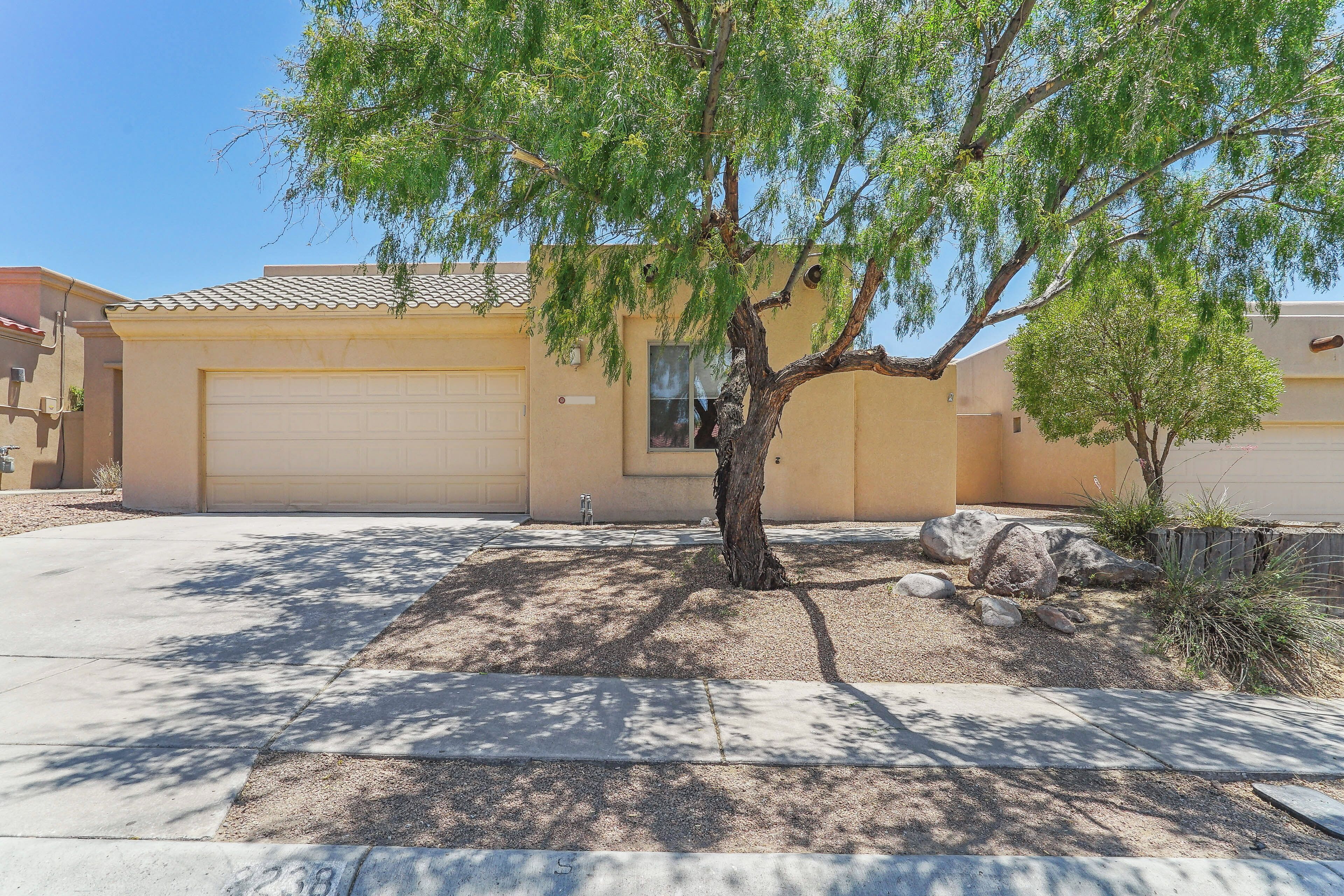 A residential property with a garage, a tree, and a well-maintained lawn.