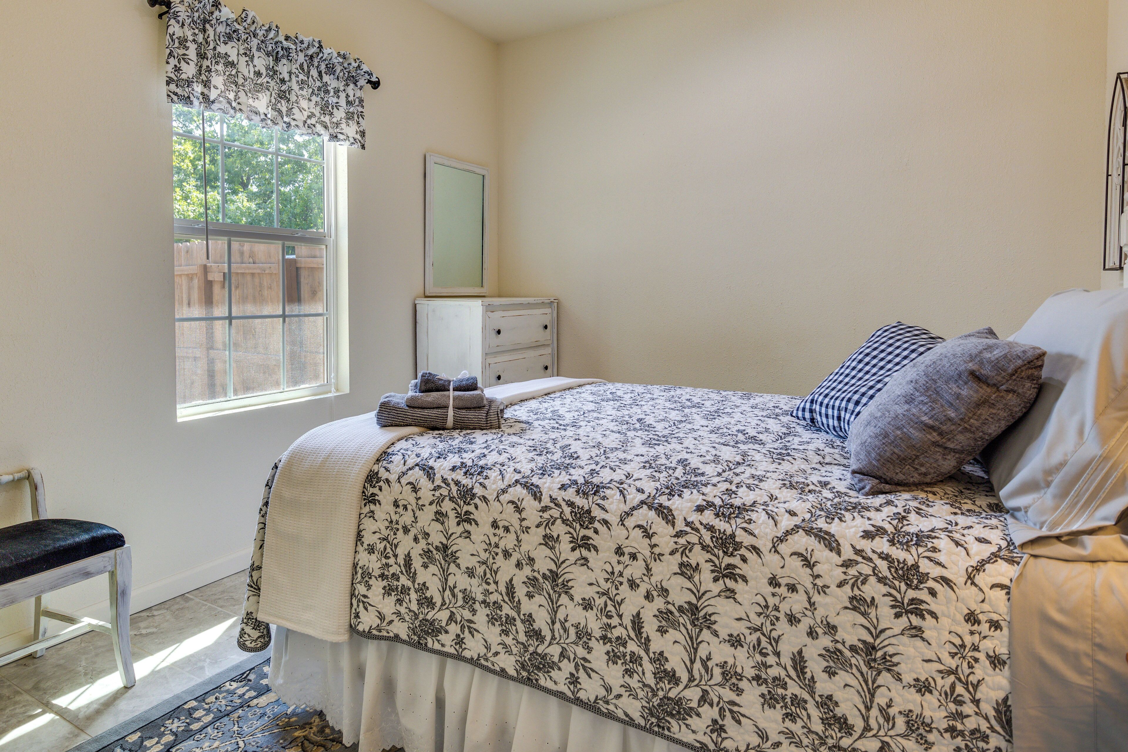 A bedroom with a bed, a dresser, a window with a view, and a chair.