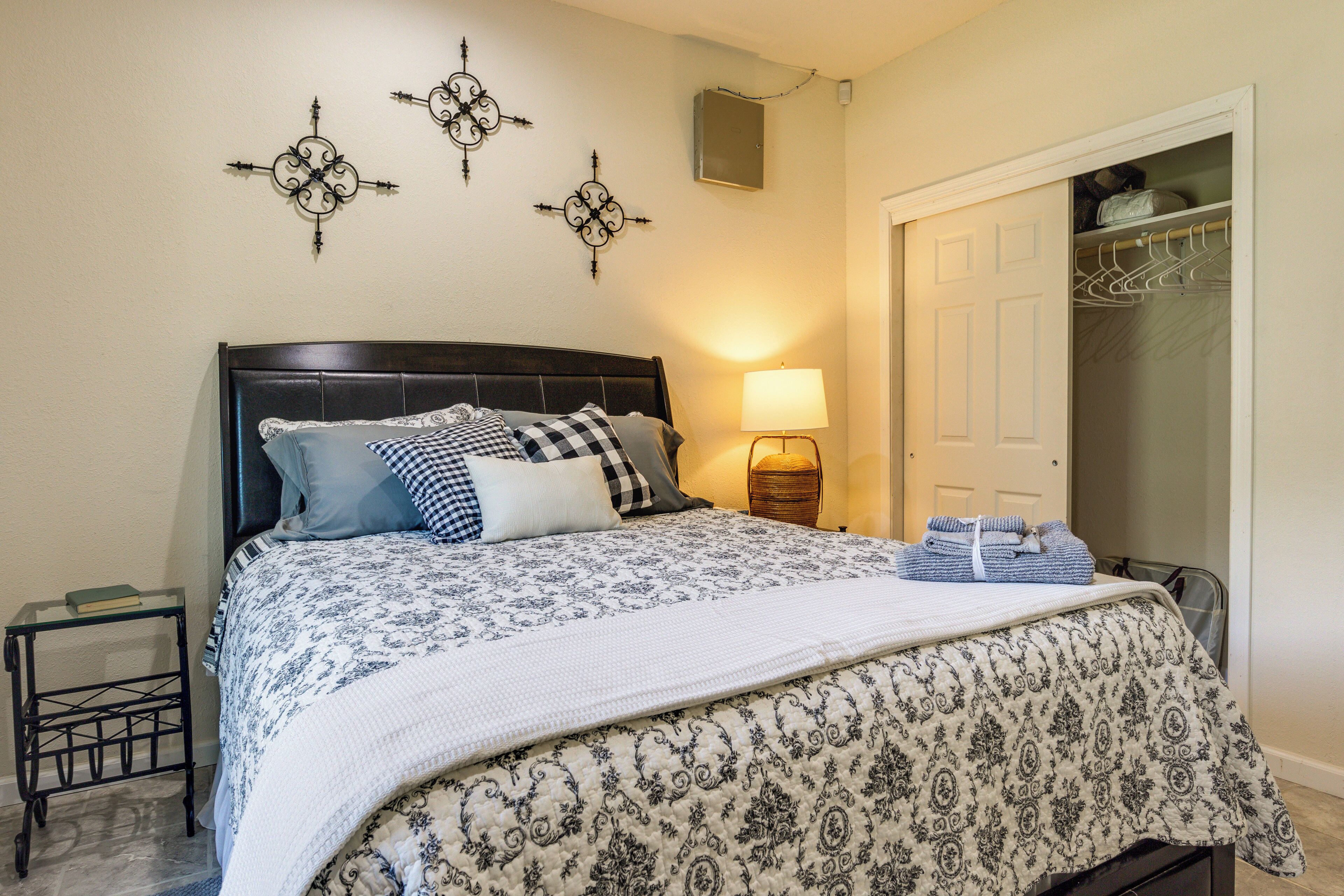 A neatly made bed with a patterned bedspread, a bedside lamp, and a small table with a book.