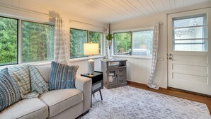 A cozy living room with a beige sofa, patterned cushions, a side table with a lamp, a gray cabinet, and a patterned rug. - Hendersonville Haven w/ Fire Pit, Grill, Deck! (Hendersonville)