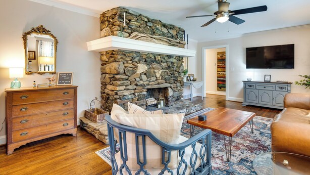 A living room with a stone fireplace, wooden furniture, and a television mounted on the wall. - Hendersonville Haven w/ Fire Pit, Grill, Deck! (Hendersonville)
