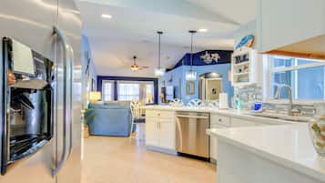 A modern kitchen with a refrigerator, dishwasher, and a dining area with a blue sofa and chairs.
