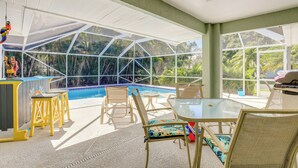 An indoor pool area with glass walls, a ceiling fan, and seating around the pool. - Jensen Beach Home w/ Heated Pool! (Jensen Beach)