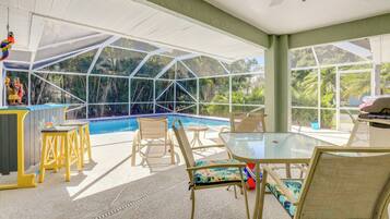 An indoor pool area with glass walls, a ceiling fan, and seating around the pool.