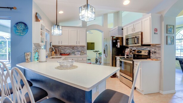 A modern kitchen with white cabinets, a central island, and stainless steel appliances. - Jensen Beach Home w/ Heated Pool! (Jensen Beach)