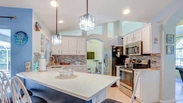 A modern kitchen with white cabinets, a central island, and stainless steel appliances.