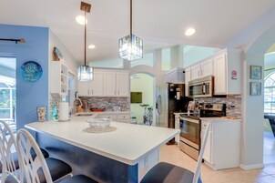 Une cuisine moderne avec des meubles blancs, un îlot central et des appareils électroménagers en acier inoxydable.