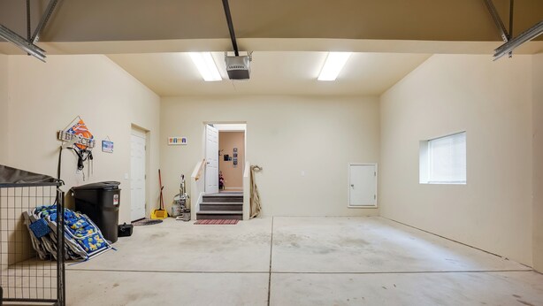 Een ruime garage met een betonnen vloer, een metalen deur en een raam.