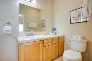 A bathroom with a sink, mirror, toilet, and wooden cabinets. - Gold Beach Retreat: Private Hot Tub + Ocean Views! (Gold Beach)