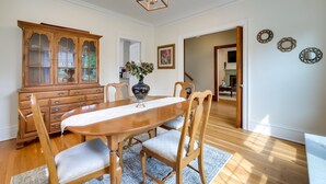 A dining room with a wooden table, chairs, a cabinet, and a vase with flowers. - Cleveland Heights Retreat: Close to Everything! (Cleveland Heights)