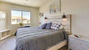 Une chambre à coucher comprenant un lit, une table de chevet, un bureau, une fenêtre et un ventilateur de plafond.