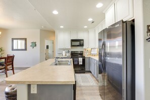 A modern kitchen with white cabinets, stainless steel appliances, and a large island.