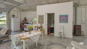 A spacious living area with a dining table set for four, a sofa, and a kitchen in the background. - Coffeyville Countryside Studio w/ Fire Pit! (Coffeyville)