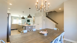 A spacious kitchen with a wooden dining table, white chairs, and a chandelier. - Beaufort Getaway w/ Pool Access, 2 Mi to Downtown! (Beaufort)