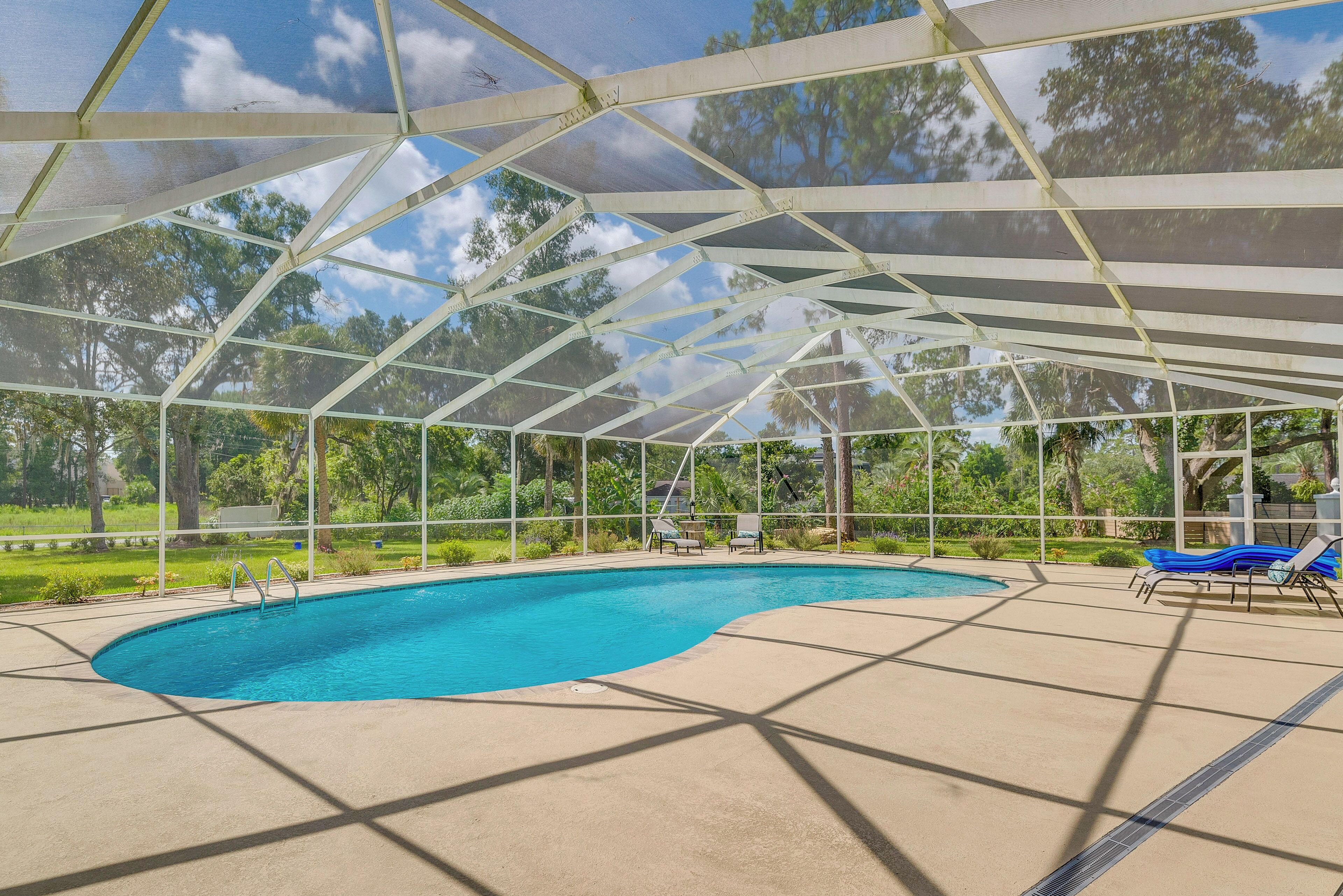 Una piscina coperta con acqua cristallina e un tetto bianco, circondata da un solarium in cemento.