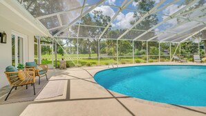 Ein überdachter Pool im Freien mit Blick auf eine grüne Landschaft und ein weißes Gebäude im Hintergrund.