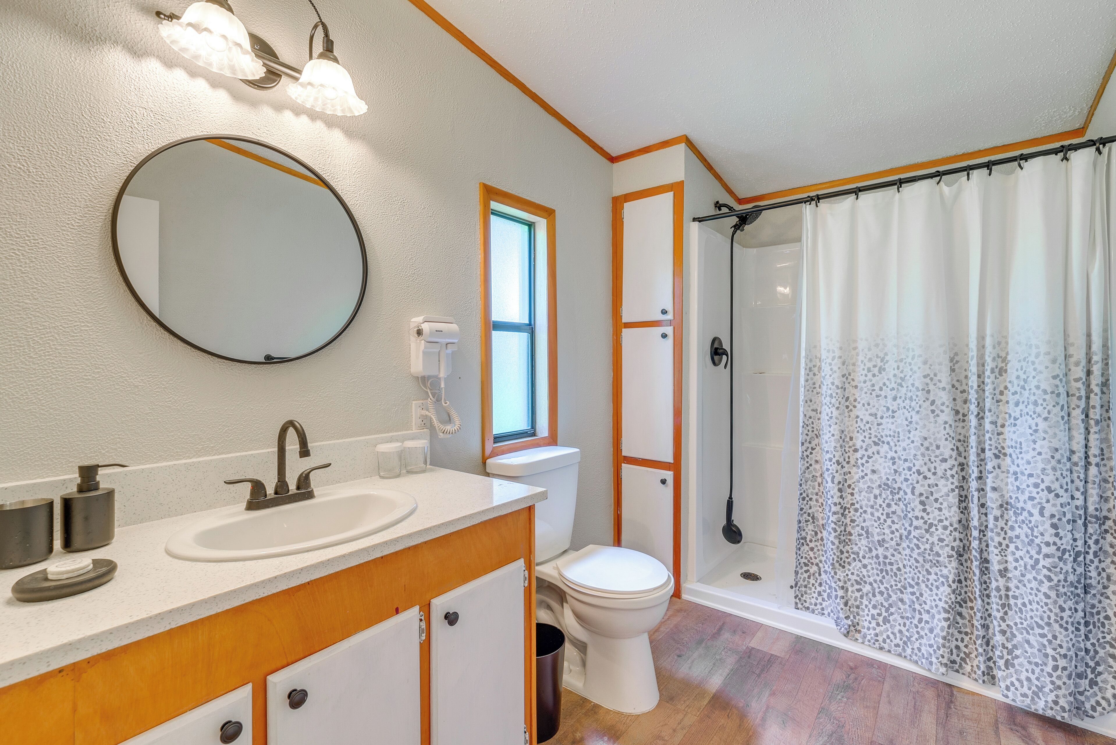 A bathroom with a sink, mirror, toilet, and shower.