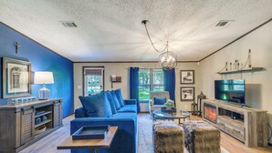 A living room with a blue sofa, a coffee table, a fireplace, and a television.