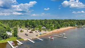 Järvenrantatontti, jossa on laituri, veneitä, hiekkaranta ja pysäköintialue.