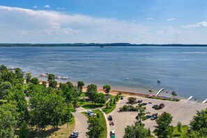 A lakeside view with a parking area, boats, and a distant shoreline.