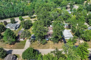 An aerial view of a residential area with houses surrounded by trees, a road, and utility lines.
