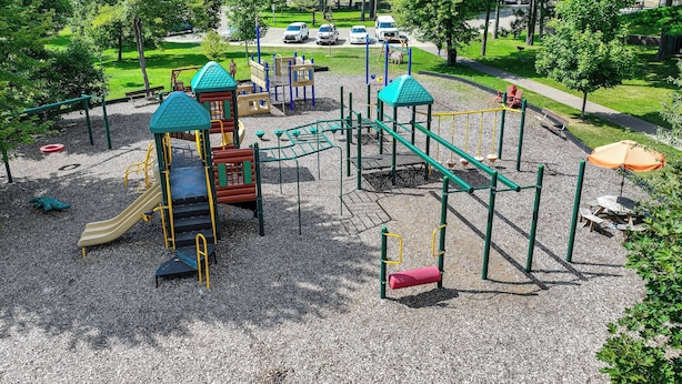 Leikkikentällä on monenlaisia leikkivälineitä, piknik-alue ja taustalla parkkipaikka.