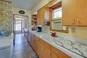 A kitchen with wooden cabinets, a white countertop, a sink, and a window with blinds.
