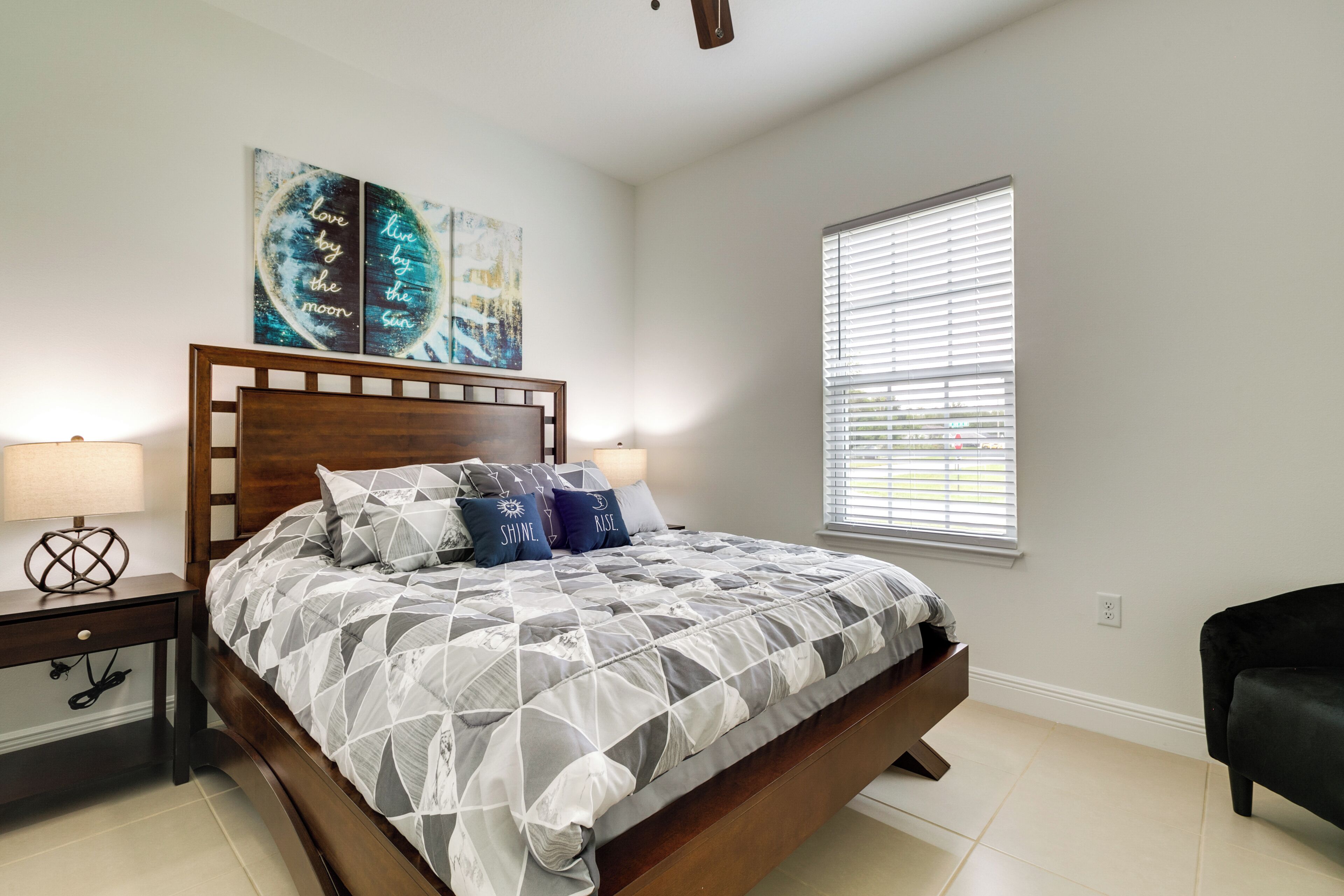 A bedroom with a bed, nightstands, a window, and artwork on the wall.