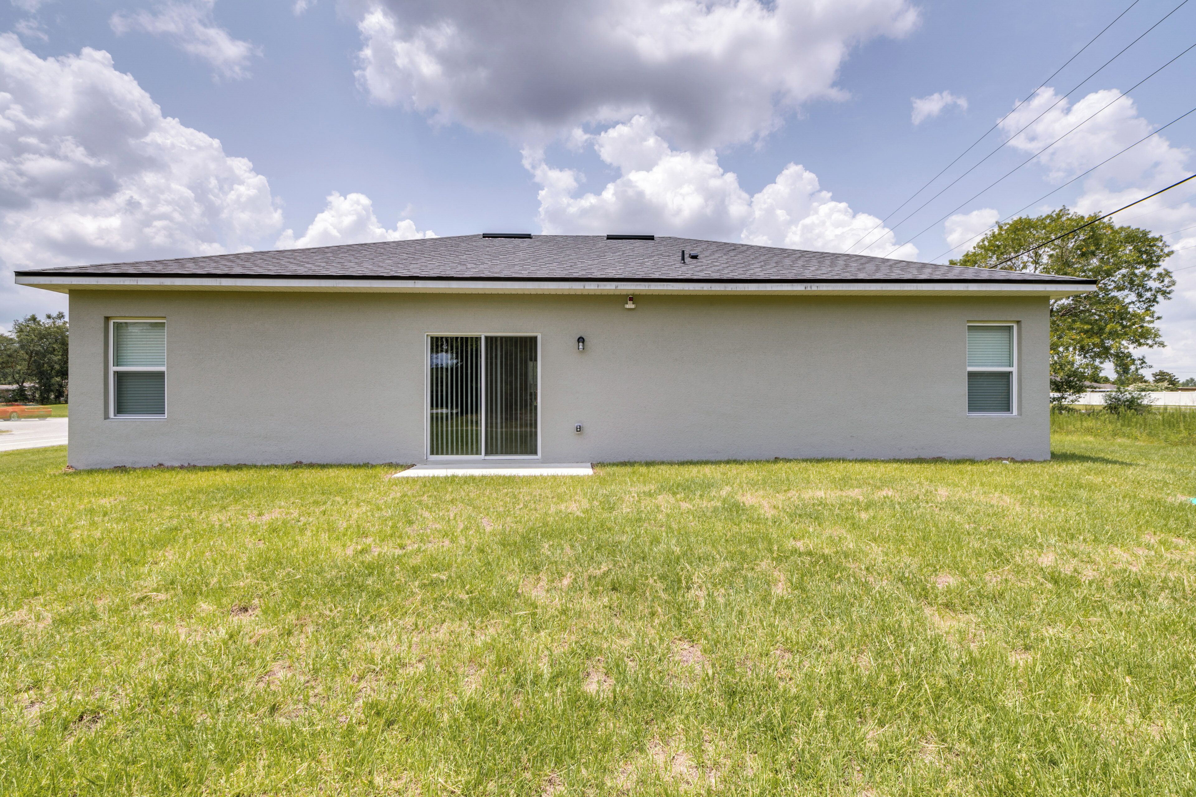 A modern single-story house with a flat roof, a front door, and two windows on the side.