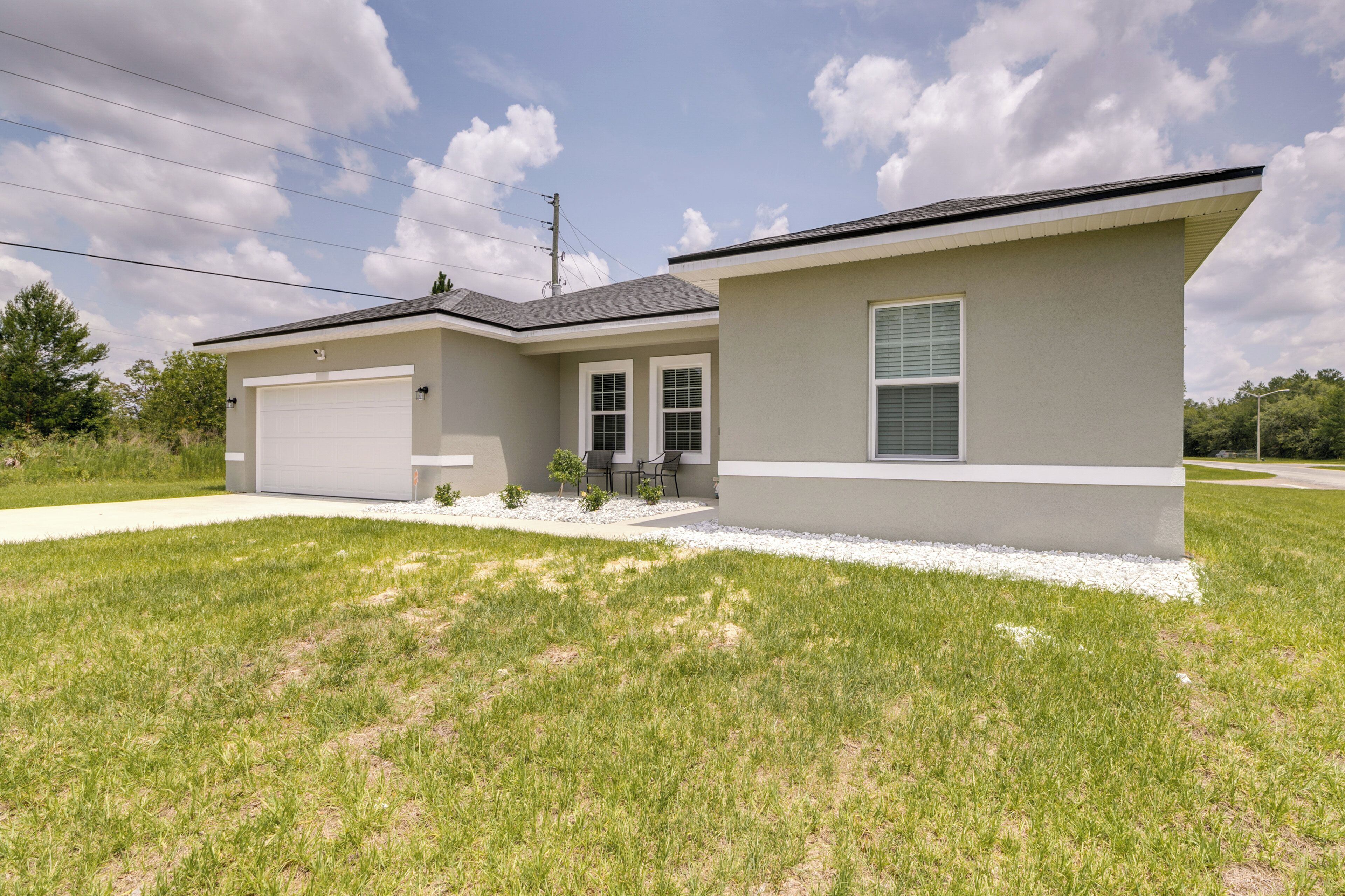 A modern single-story house with a garage, a small patio with outdoor furniture, and a well-maintained lawn.