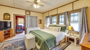 A bedroom with a bed, a television, a chair, and a window with curtains. - Eureka Springs Vacation Rental < Half-mi to Dtwn! (Eureka Springs)