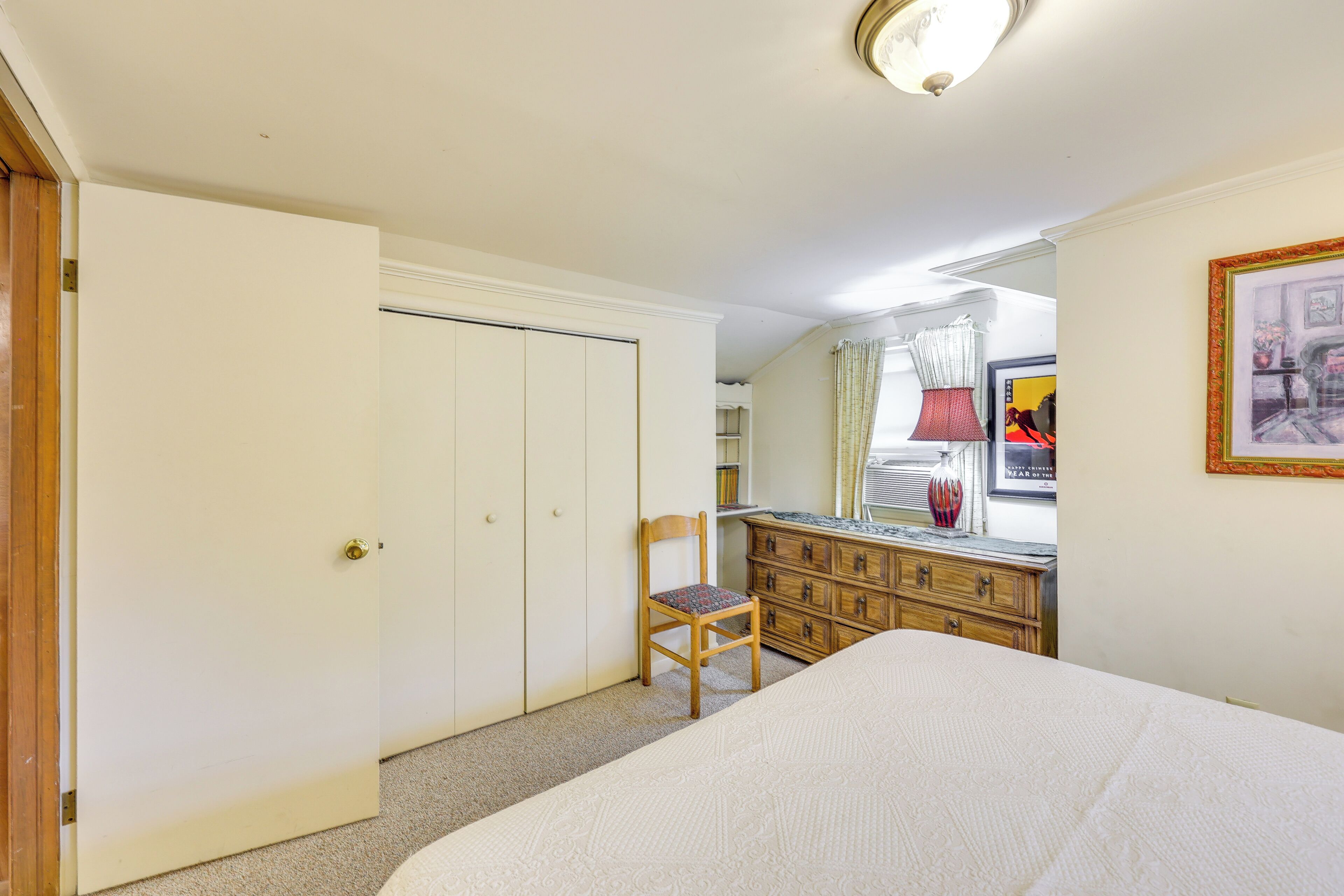 A bedroom with a bed, a wooden chair, a dresser, and a wardrobe.