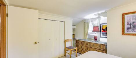 A bedroom with a bed, a wooden chair, a dresser, and a wardrobe.