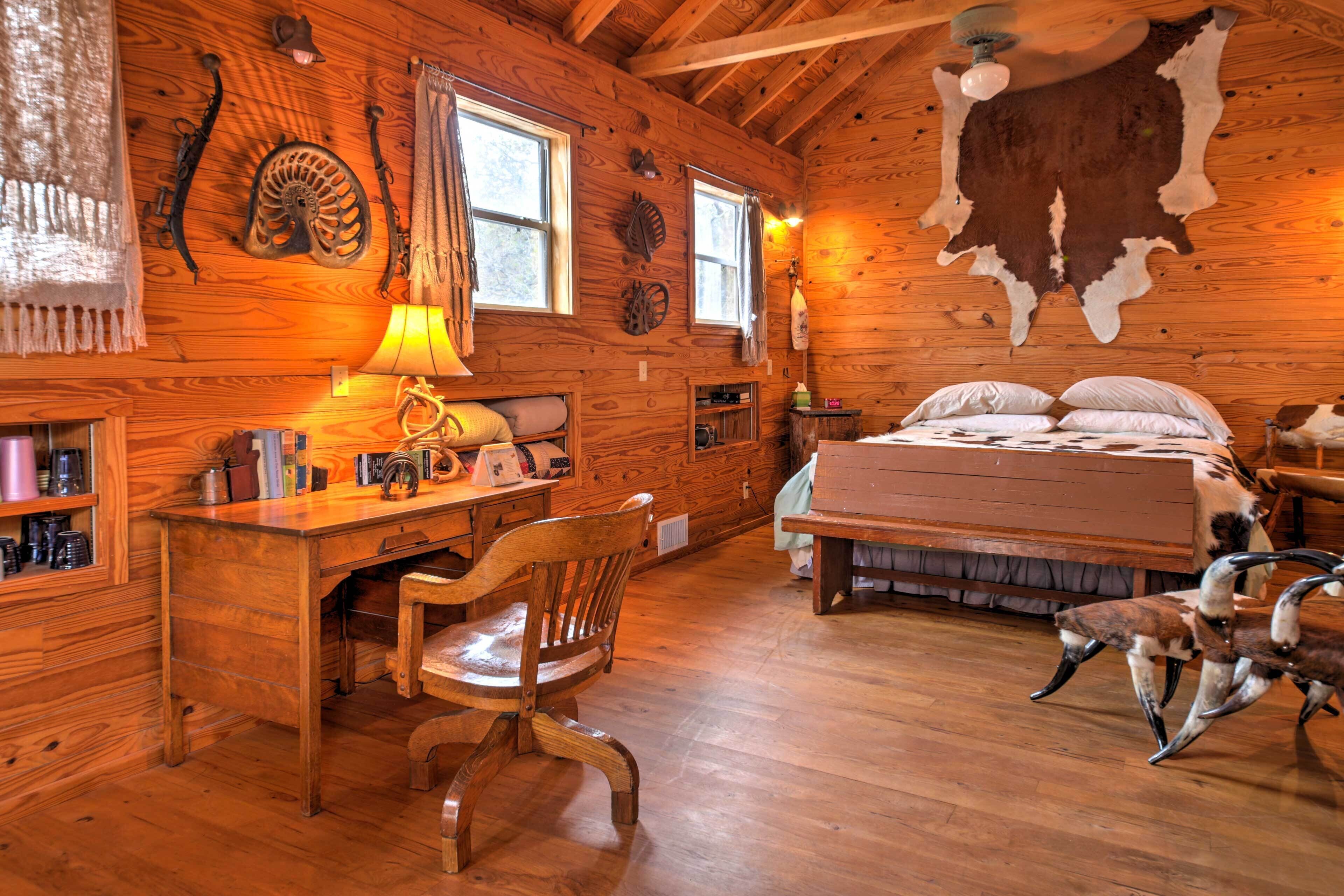 Ein rustikales Blockhaus-Interieur mit einem Holztisch, einem Bett und einem großen Fell an der Wand.
