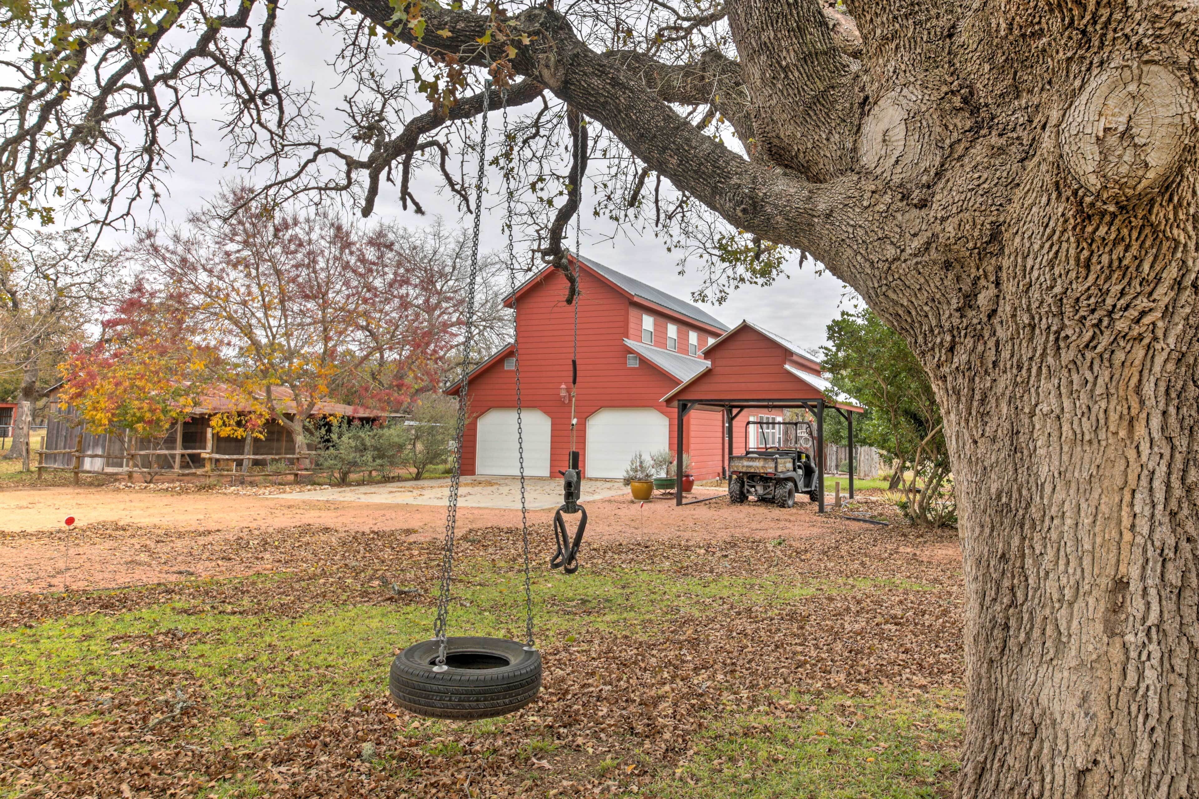 Una casa roja con un columpio bajo un árbol grande.