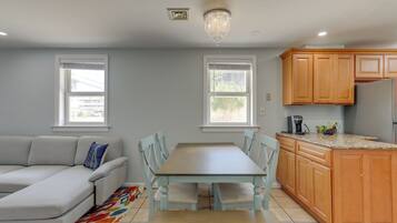 A modern kitchen with wooden cabinets, a dining table, and a gray sofa.