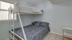 Ein Schlafraum mit Etagenbetten, einem Fenster, einer Kandelaber und einem kleinen Tisch.