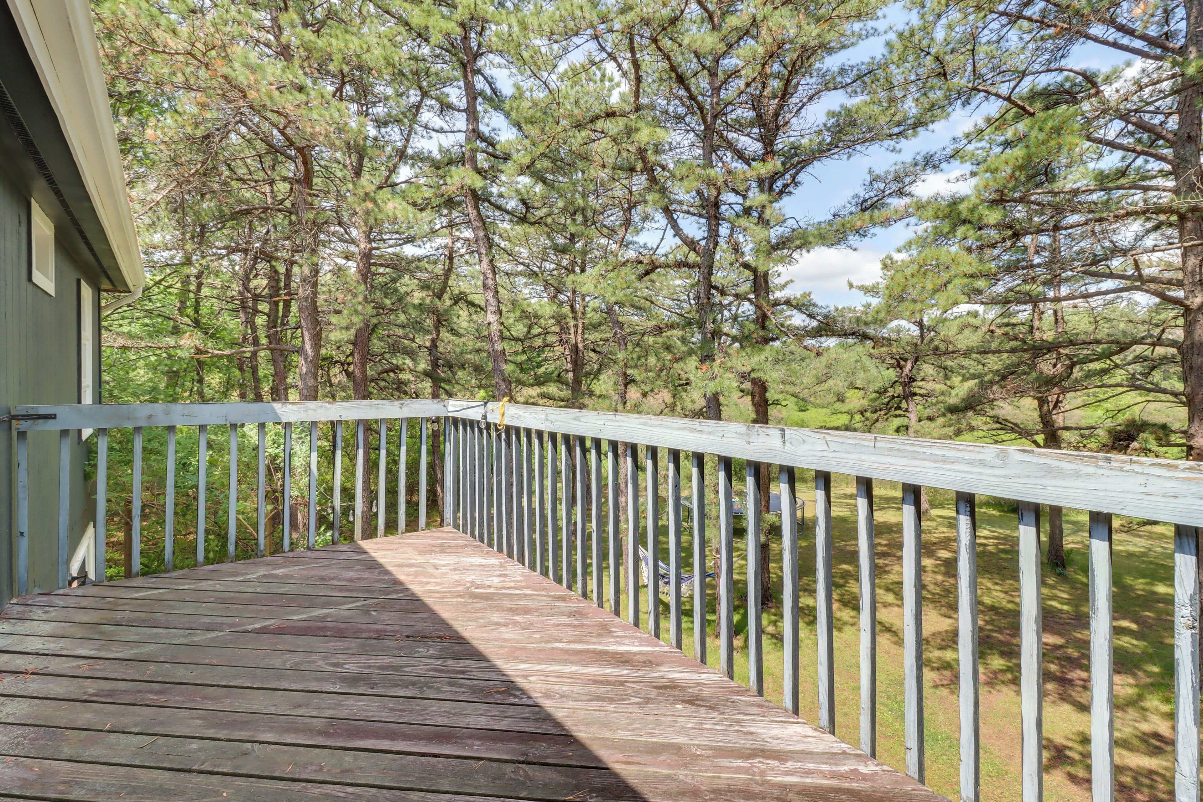 A wooden deck with a railing overlooking a forested area.