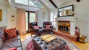 Ein geräumiges Wohnzimmer mit Kamin, Ledersofas und einem großen Fenster.