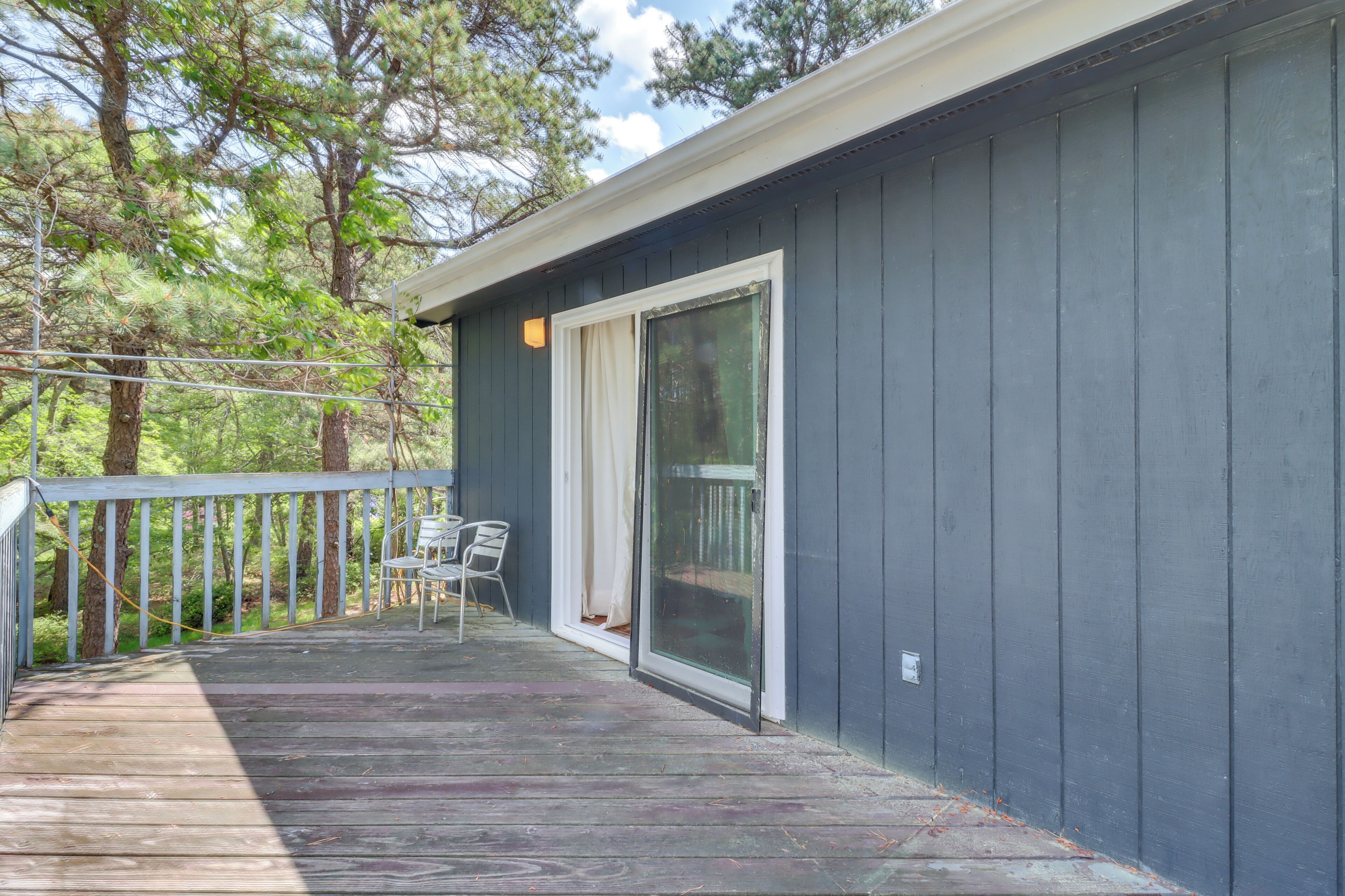 Une terrasse en bois avec une rambarde, une porte-fenêtre coulissante et une chaise.