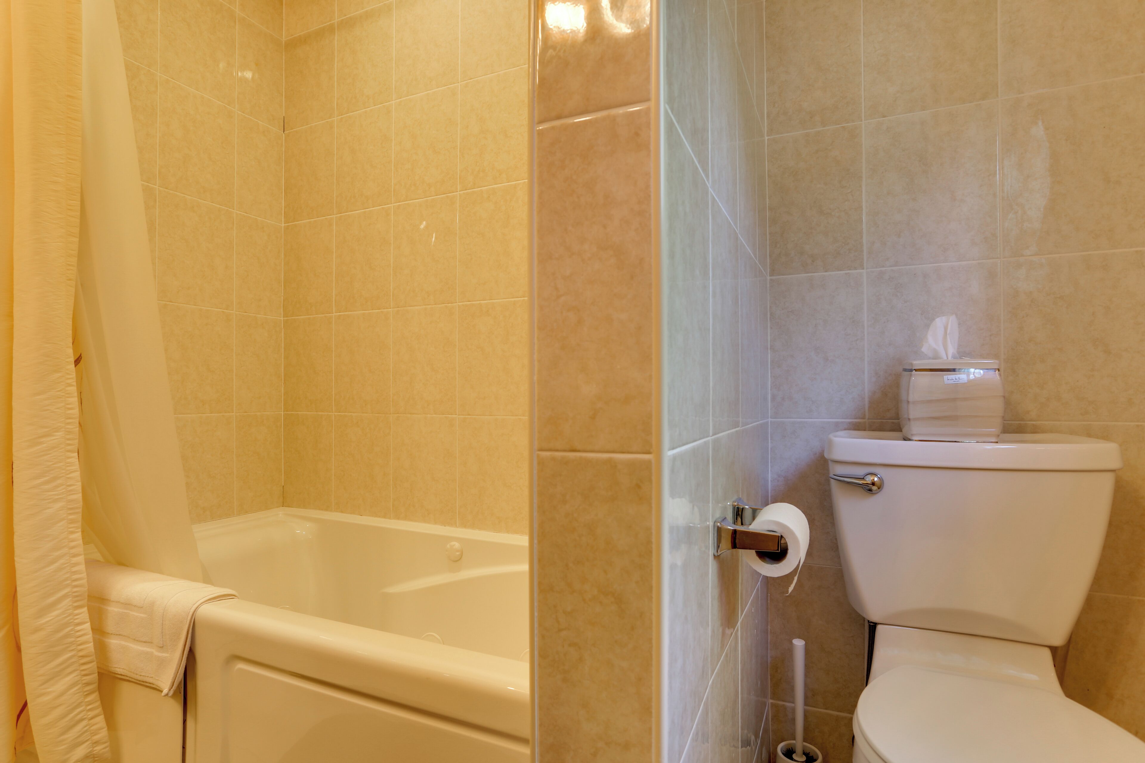 A bathroom with a bathtub, toilet, and a shower curtain.