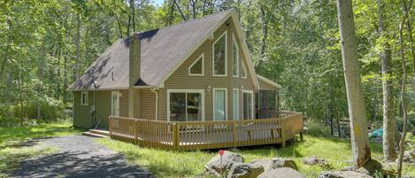 A cabin with a deck, surrounded by trees.