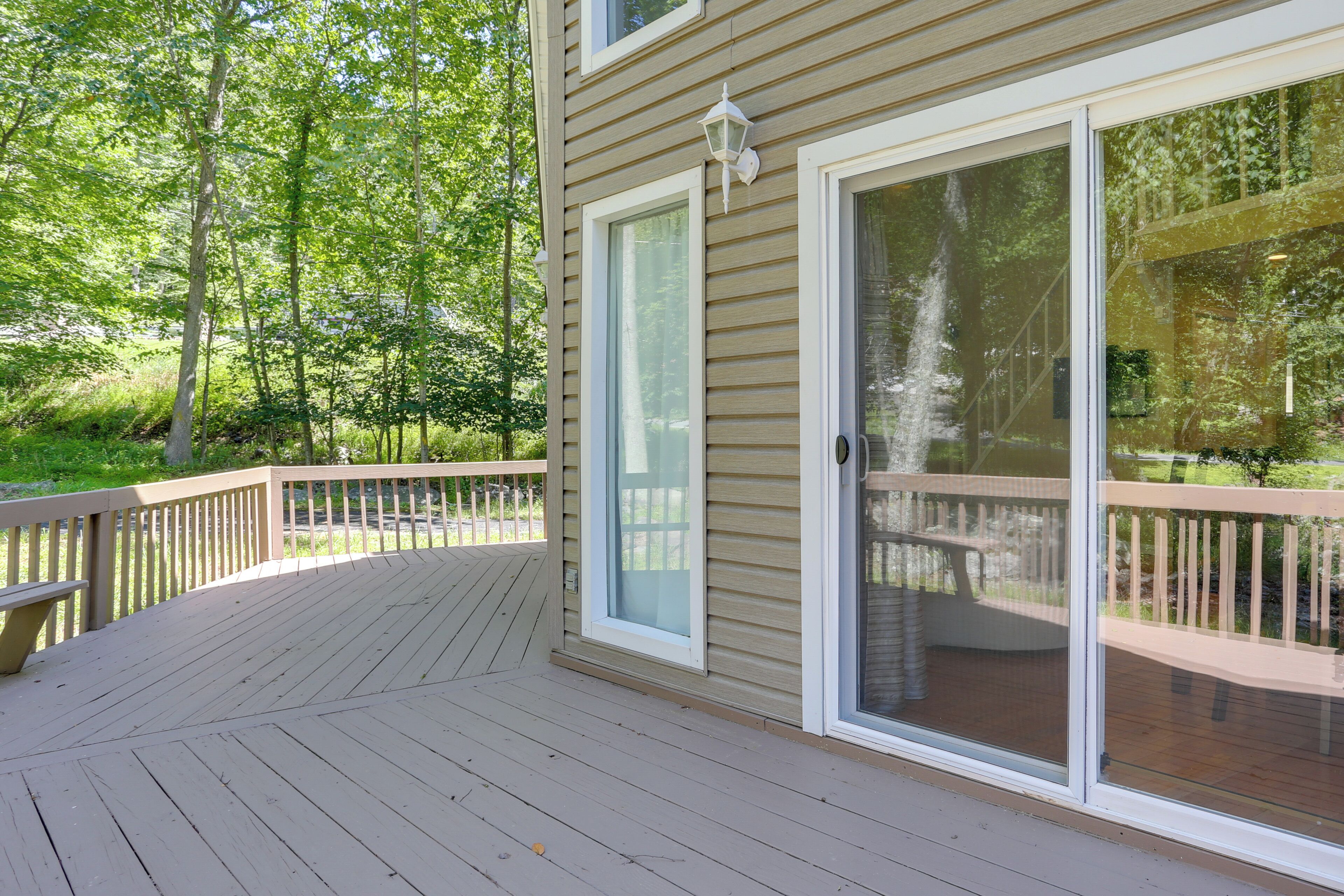 A deck with a glass door leading to a covered patio area.