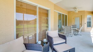 A covered patio area with wicker furniture, a table, and a ceiling fan. - Family-friendly Spring Hill Vacation Home w/ Lanai (Spring Hill)