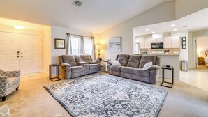A living room with two sofas, a patterned rug, a small side table, and a kitchen area with appliances. - Family-friendly Spring Hill Vacation Home w/ Lanai (Spring Hill)