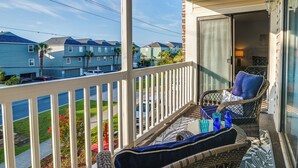 A balcony with wicker furniture, a view of neighboring houses, and a clear sky. - Ocean Access & Balcony: Surfside Beach Condo (Myrtle Beach)