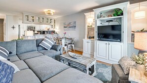 A modern living room with a grey sectional sofa, a coffee table, and a TV in a white entertainment unit. - Ocean Access & Balcony: Surfside Beach Condo (Myrtle Beach)