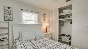 A neatly arranged bedroom with a bed, bedside table, lamp, and a wardrobe with shelves.
