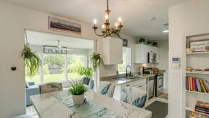 A modern kitchen with a dining area, a chandelier, and a view of the outdoors.